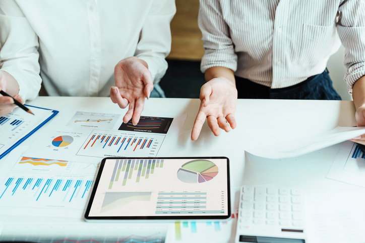 Two people discussing economics while looking over charts and graphs